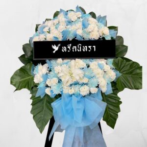พวงหรีดดอกไม้สด โทนสีขาว ฟ้า ดีไซน์สุภาพสดใส ตกแต่งดอกเบญจมาศ ลิลลี่ และดอกมัม พร้อมใบไม้สีเขียวขนาดใหญ่ ดูเรียบหรูและสง่างาม