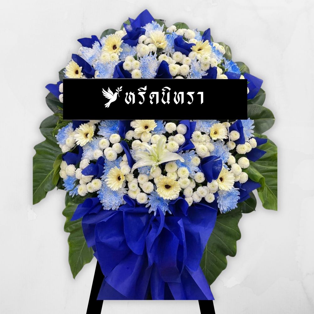 พวงหรีดดอกไม้สดโทนสีน้ำเงินขาว ดีไซน์เรียบหรู ตกแต่งด้วยดอกเยอบีร่า เบญจมาศ ลิลลี่ และดอกมัม พร้อมกระดาษสีน้ำเงินเข้ม ดูสุภาพและสง่างาม